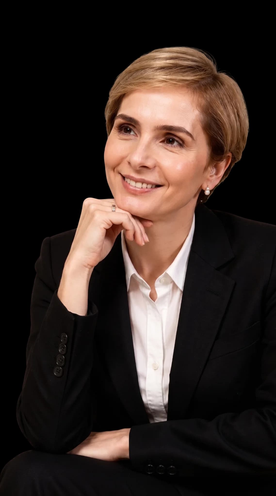 Denize Ortiz em retrato editorial com blazer preto.